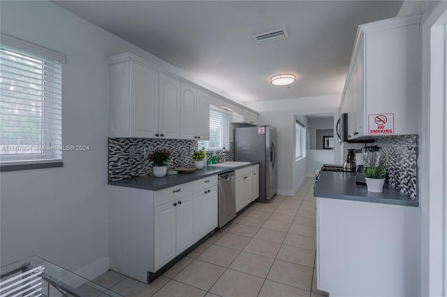 kitchen featuring light tile flooring, backsplash, sink, white cabinets, and appliances with stainless steel finishes