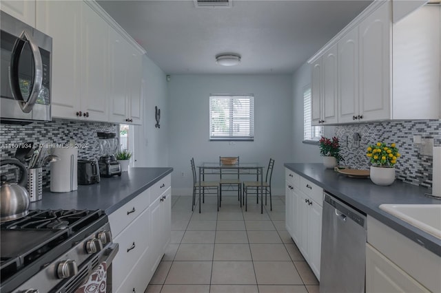 kitchen with backsplash, appliances with stainless steel finishes, light tile floors, and white cabinets