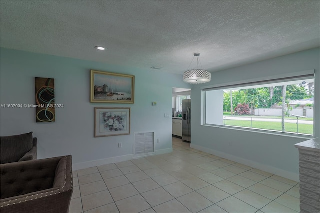 interior space with a textured ceiling and light tile flooring