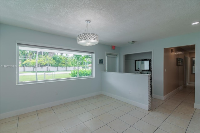 empty room with a textured ceiling and light tile floors