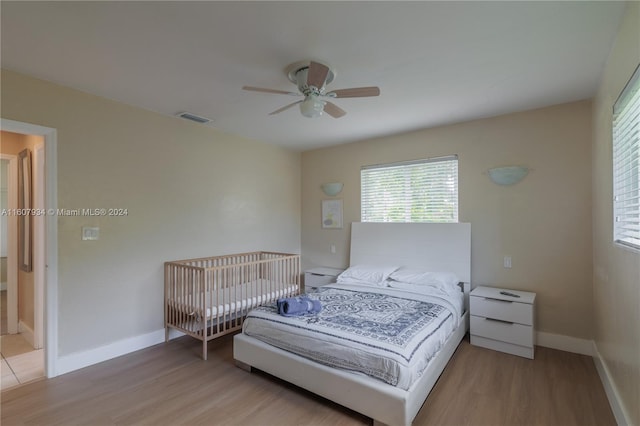 bedroom featuring ensuite bath, ceiling fan, and light wood-type flooring