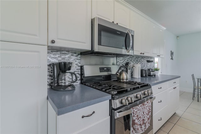 kitchen with appliances with stainless steel finishes, white cabinetry, tasteful backsplash, and light tile floors