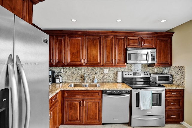 kitchen featuring stainless steel appliances, sink, tasteful backsplash, and light stone counters