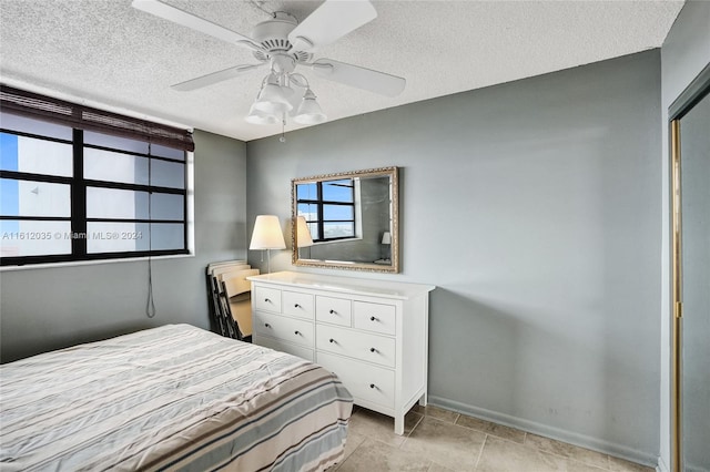 bedroom featuring ceiling fan, a textured ceiling, and light tile floors