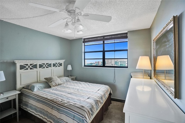 bedroom featuring ceiling fan, a textured ceiling, and dark tile floors