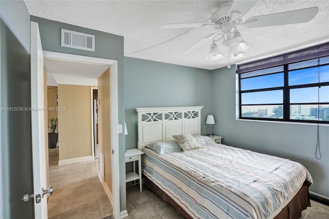 bedroom featuring a textured ceiling, ceiling fan, and light tile flooring