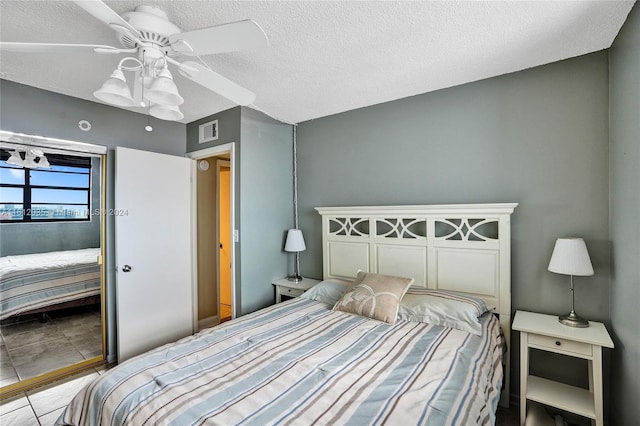 tiled bedroom featuring ceiling fan and a textured ceiling