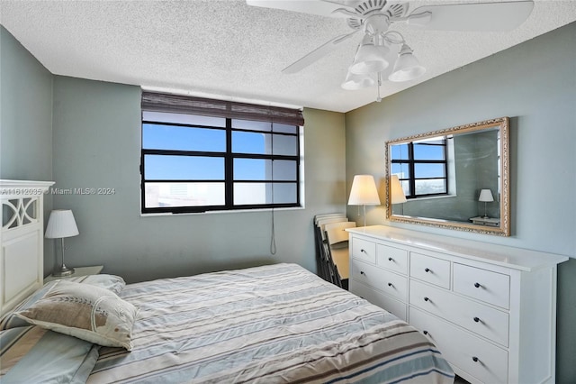 bedroom featuring ceiling fan, multiple windows, and a textured ceiling