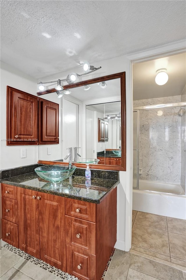 kitchen featuring dark stone counters, ceiling fan, a textured ceiling, light tile floors, and sink