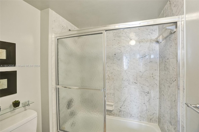 bathroom with bath / shower combo with glass door and toilet