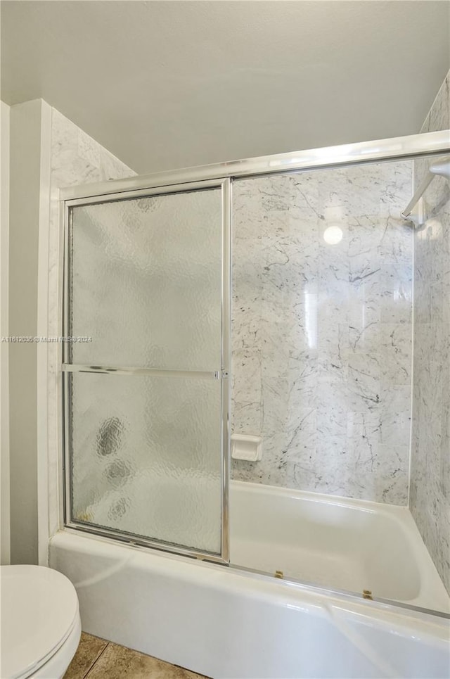 bathroom featuring enclosed tub / shower combo, toilet, and tile floors