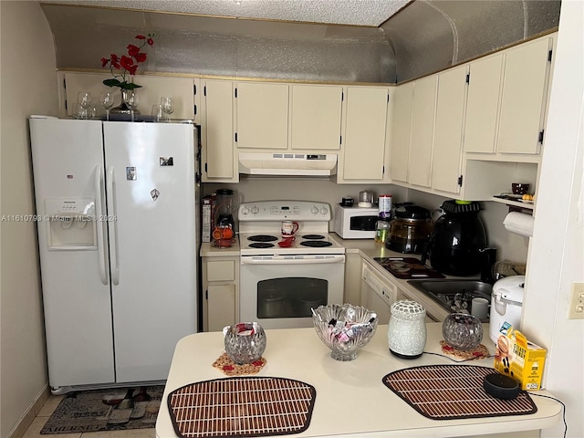 kitchen featuring tile patterned flooring, cream cabinetry, and white appliances