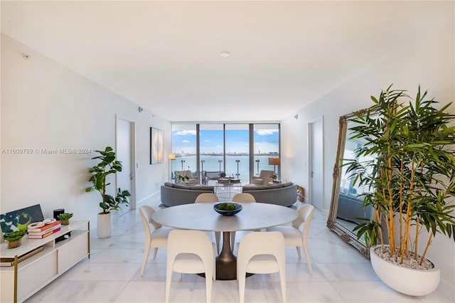 dining space featuring floor to ceiling windows, a water view, and light tile patterned floors