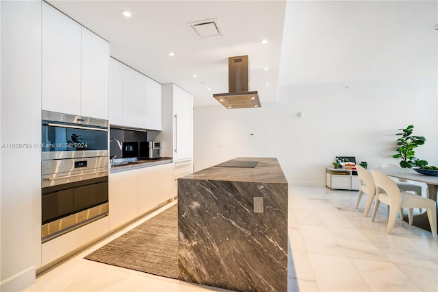 kitchen featuring white cabinetry, island range hood, sink, and stainless steel double oven