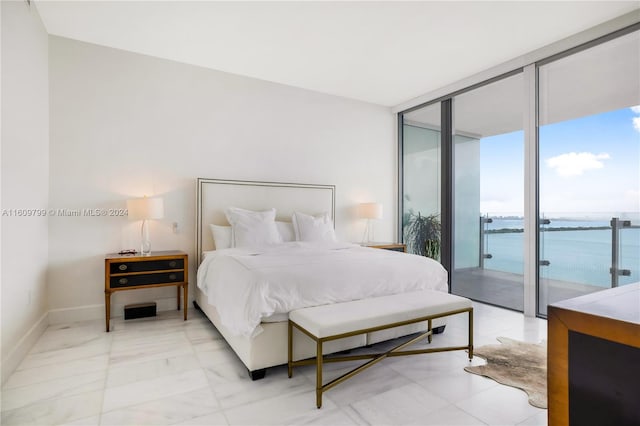 bedroom with a water view, a wall of windows, and access to outside