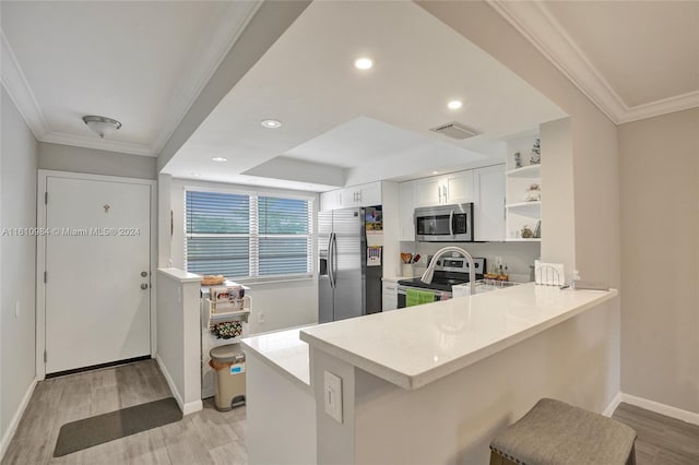 kitchen with light hardwood / wood-style flooring, kitchen peninsula, white cabinets, stainless steel appliances, and a kitchen breakfast bar