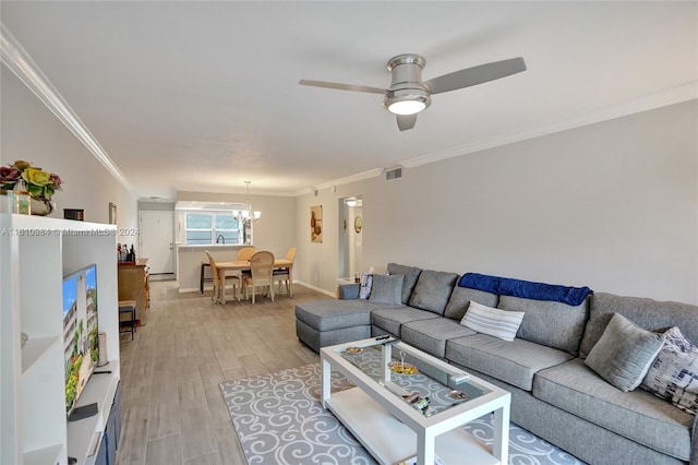 living room featuring ceiling fan with notable chandelier, wood-type flooring, and ornamental molding