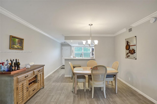 dining room featuring sink, light hardwood / wood-style floors, crown molding, and a notable chandelier