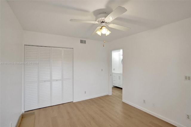 unfurnished bedroom featuring ceiling fan, light wood-type flooring, ensuite bathroom, and a closet