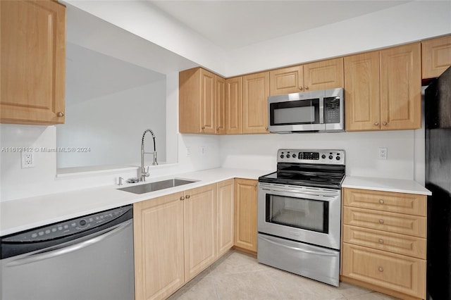 kitchen with light tile patterned floors, stainless steel appliances, light brown cabinetry, and sink