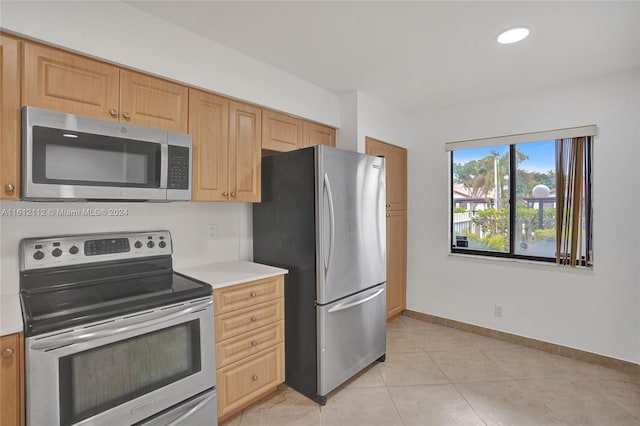 kitchen with light brown cabinets, light tile patterned floors, and appliances with stainless steel finishes