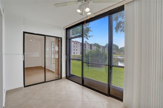 unfurnished sunroom featuring ceiling fan and a water view