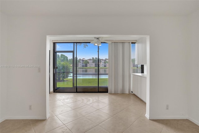 spare room featuring light tile patterned floors, a water view, and ceiling fan