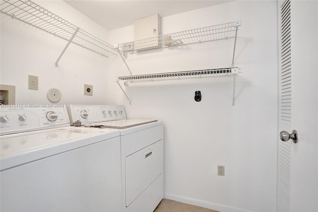 clothes washing area featuring washer and clothes dryer and light tile patterned floors