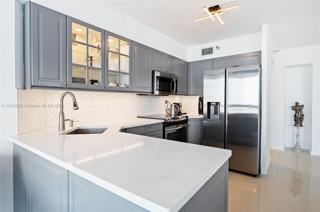 kitchen with kitchen peninsula, tasteful backsplash, stainless steel appliances, gray cabinets, and sink