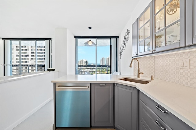 kitchen featuring gray cabinetry, stainless steel dishwasher, pendant lighting, sink, and tasteful backsplash