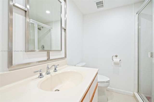 bathroom featuring a shower with shower door, vanity with extensive cabinet space, toilet, and tile floors