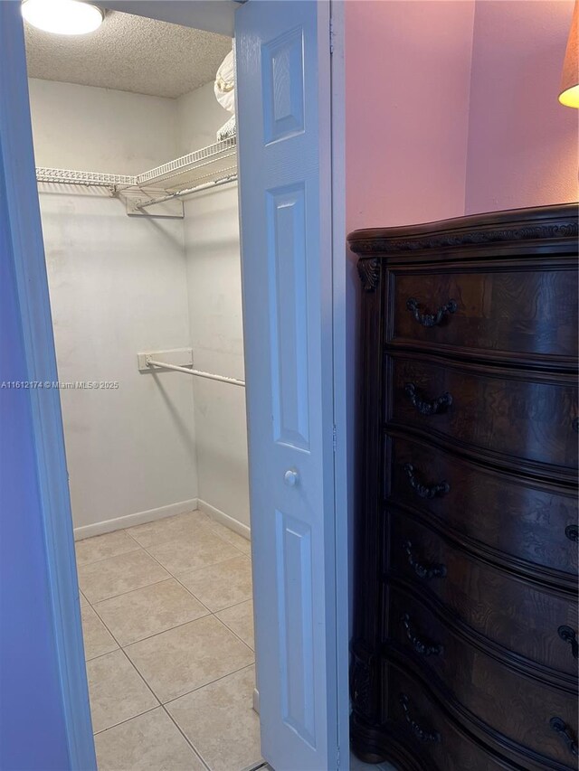 bedroom with ceiling fan, ornamental molding, a textured ceiling, and light tile patterned floors