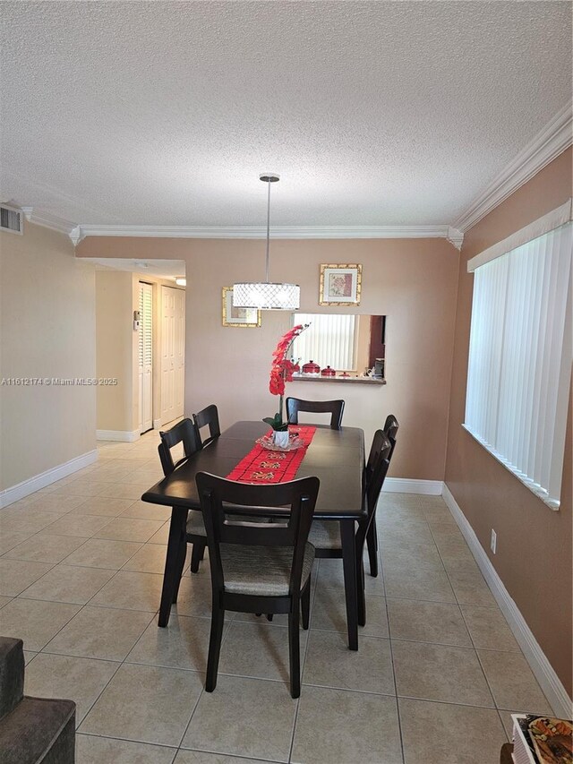 tiled dining area featuring crown molding and a textured ceiling