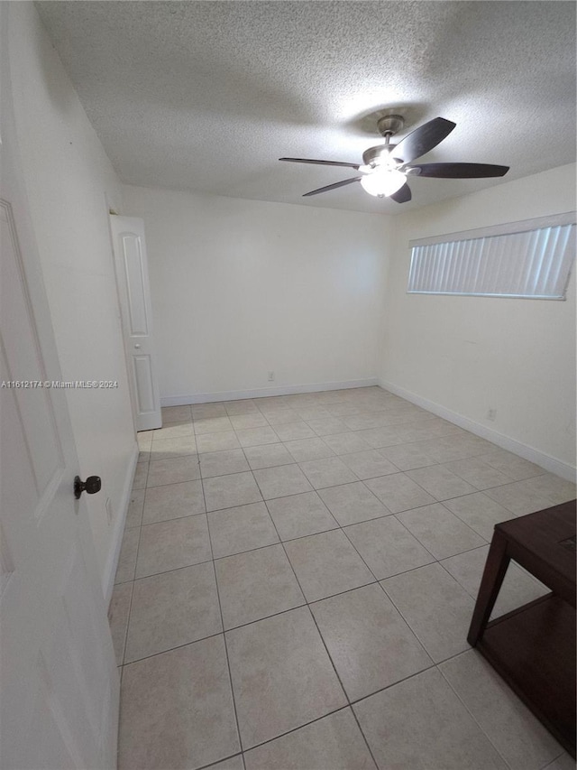 unfurnished room with ceiling fan, light tile patterned flooring, and a textured ceiling