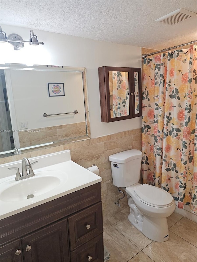 bathroom featuring a textured ceiling, vanity, tile walls, and toilet