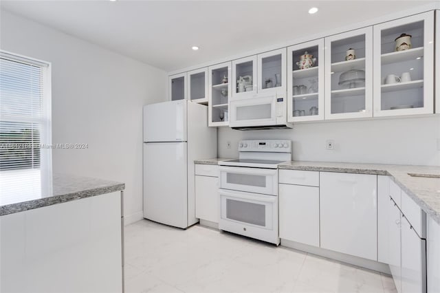 kitchen featuring light stone counters, white cabinets, white appliances, and light tile floors