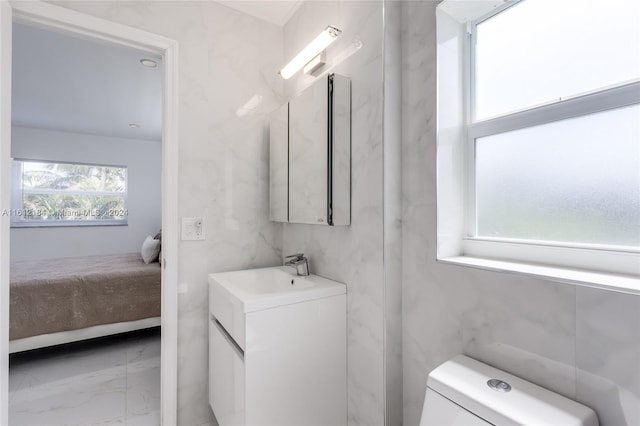 bathroom with tile flooring, oversized vanity, tile walls, and toilet