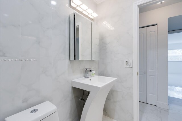 bathroom with tile flooring, tile walls, and toilet