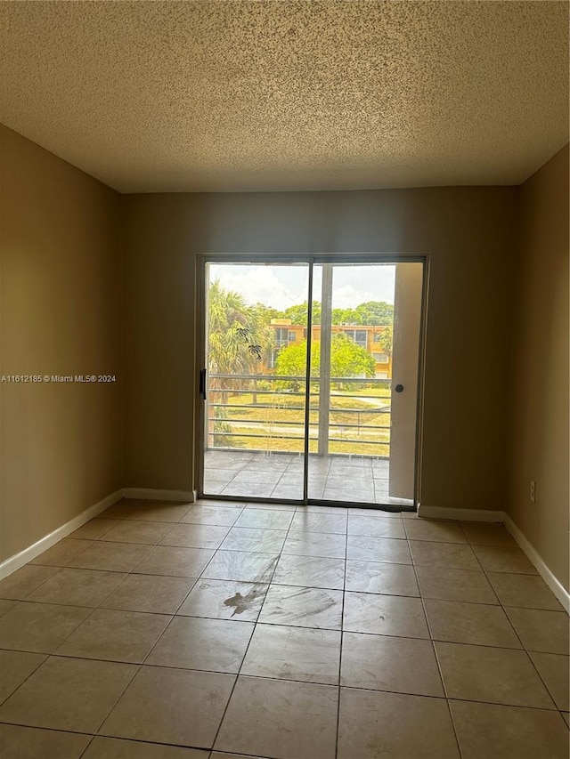 tiled empty room with a textured ceiling