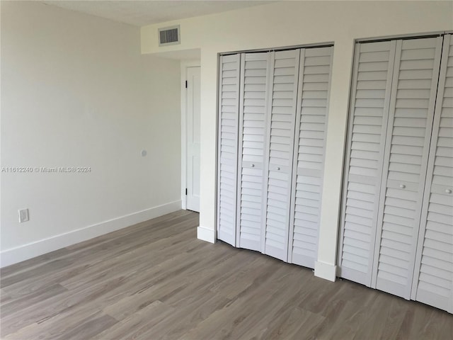 unfurnished bedroom featuring hardwood / wood-style floors and multiple closets