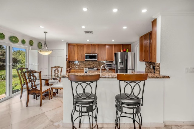 kitchen featuring appliances with stainless steel finishes, decorative light fixtures, decorative backsplash, dark stone countertops, and kitchen peninsula