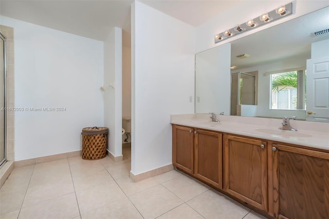 bathroom featuring tile patterned flooring, vanity, toilet, and a shower with shower door