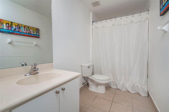 bathroom with toilet, vanity, and tile patterned flooring