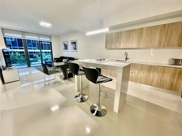 kitchen featuring a breakfast bar, light brown cabinets, sink, a kitchen island, and a wall of windows