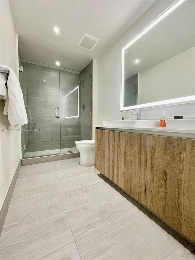 bathroom with vanity, toilet, and a shower with shower door