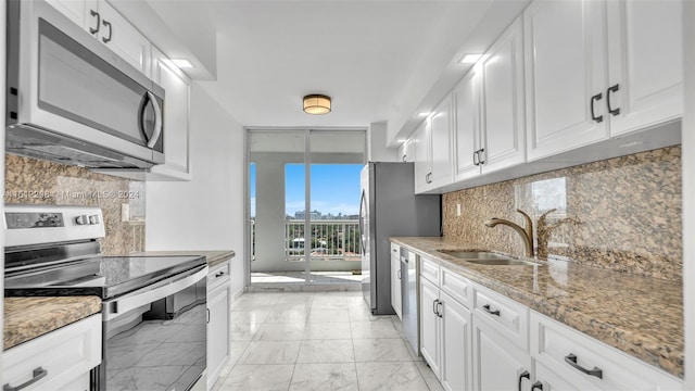 kitchen with white cabinetry, sink, backsplash, light stone counters, and stainless steel appliances