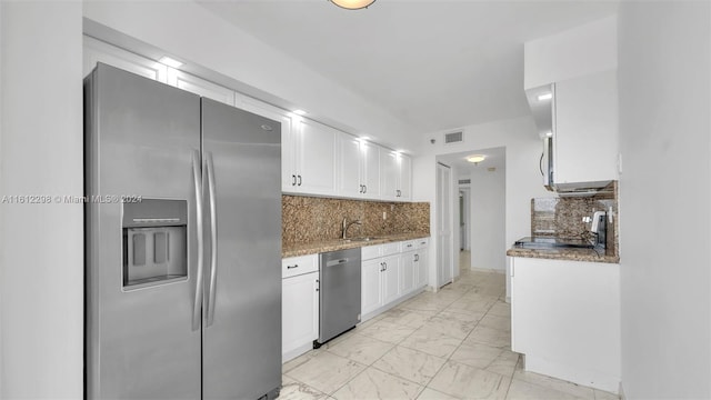 kitchen with stone countertops, white cabinetry, sink, backsplash, and stainless steel appliances