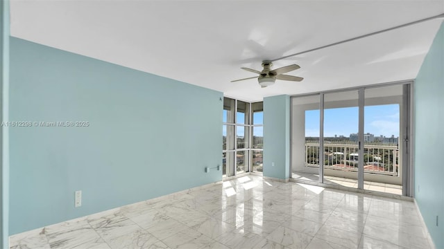 spare room featuring marble finish floor, ceiling fan, floor to ceiling windows, and a city view