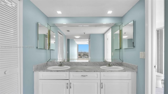 full bath featuring toilet, a closet, a sink, and double vanity