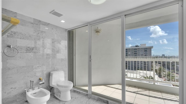 bathroom featuring tile walls, toilet, visible vents, a city view, and a bidet